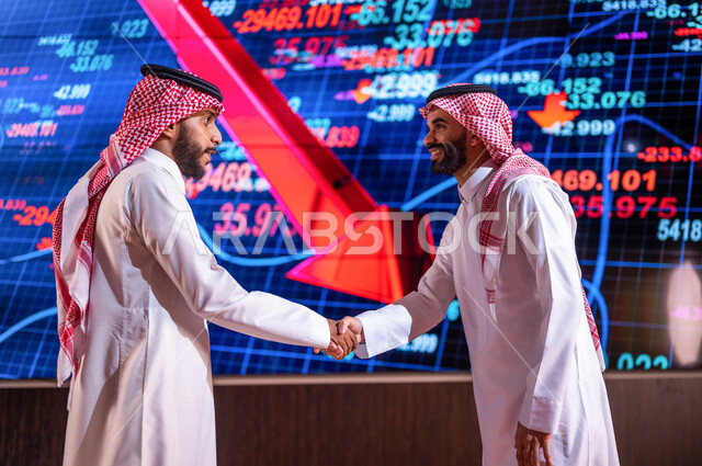 رجلان اعمال عربيان خليجيان سعوديان يتصافحان مع بعضهما ، اتفاق عمل ، صفقة ناجحة ، متابعة سوق الاوراق المالية ، متابعة صعود ونزول الاسهم ، شراء وبيع الاسهم في البورصة ، الاستثمار المالي والاقتصادي