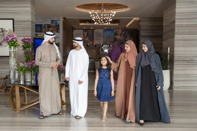 Enjoying happy family moments, preparing for an enjoyable tourist trip with the family, exchanging conversations with expressions of joy and happiness. An Emirati Gulf Arab family dressed in traditional attire is walking into the hotel reception area. Enjoying happy family moments, preparing for an enjoyable tourist trip with the family, exchanging conversations with expressions of joy and happiness. An Emirati Gulf Arab family dressed in traditional attire is walking into the hotel reception area.