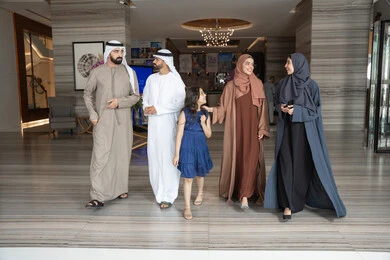 الاستعداد لقضاء رحلة سياحية ممتعه مع العائلة، تبادل الاحاديث بتعابير السرور و السعادة,عائلة عربيه خليجيه اماراتية ترتدي الزي التقليدي يسيرون داخل مدخل الاستقبال فى الفندق, الاستمتاع في قضاء الوقت مع الأهل