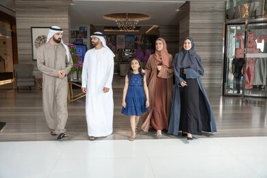تبادل الاحاديث بتعابير السرور و السعادة, الاستعداد لقضاء رحلة سياحية ممتعه مع العائلة,عائلة عربيه خليجيه اماراتية ترتدي الزي التقليدي يسيرون داخل مدخل الاستقبال فى الفندق, الاستمتاع في قضاء الوقت مع الأهل