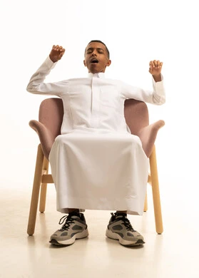 الشعور بالتعب والحاجة إلى النوم، بورتريه لرجل عربي خليجي سعودي يرتدي الثوب التقليدي يجلس على كرسي مريح، الاستمتاع بالأجواء الهادئة، مفهوم الراحة والاسترخاء, خلفية بيضاء