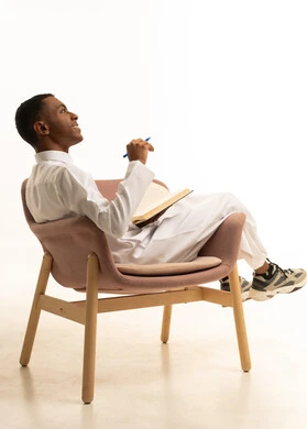 تطوير المناهج التعليمية في السعودية، إيماءات الاجتهاد والتفوق، مراجعة الدروس للمذاكرة والاختبارات المدرسية, بورتريه من الجانب لشاب مراهق عربي خليجي سعودى مبتسم يرتدي الثوب التقليدى مستلقي على الكرسي يمسك بيده الكتاب المدرسي والقلم، خلفية بيضاء