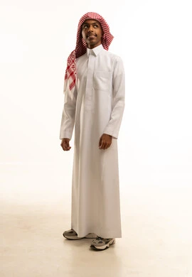اجتياز الاختبارات بتفوق ودرجات عليا، الوقوف باستعداد واستقامة، بورتريه لفتى عربي خليجي سعودي مبتسم يرتدي الثوب التقليدي والشماغ ينظر إلى شىء ما، صورة الجسم بالطول الكامل، خلفية بيضاء