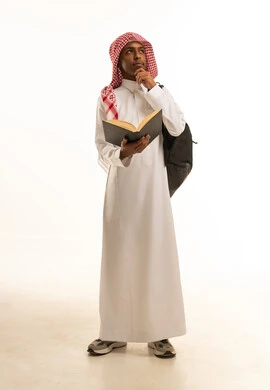 بورتريه لشاب عربي خليجي سعودي يرتدي الثوب التقليدي والشماغ و حقيبة ظهر يقوم بقراءة كتاب,  تحضير الدروس للوصول إلى النجاح، مراجعة الدروس اليومية, الاستعداد للعام الدراسي الجديد، تطوير المناهج التعليمية في السعودية, النظرالى شىء ما، خلفية بيضاء