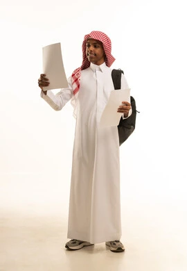 ايماءات وتعابير الفوز والنجاح، بورتريه لطالب عربي خليجي سعودي مبتسم يرتدي الثوب التقليدي و الشماغ و حقيبة الظهر المدرسية يحمل بيده مجموعة أوراق، اجتياز الاختبارات بتفوق ودرجات عليا، صورة الجسم بالكامل، خلفية بيضاء