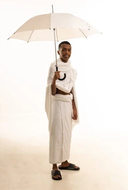 تعابير السرور بالاستعداد لأداء فريضة الحج،  بورتريه لشاب عربي خليجي سعودى يرتدي ثياب الإحرام يحمل بيده مظلة شمسية للحماية والتظلل،  زيارة المشاعر المقدسة في مكة المكرمة، الجسم بالطول الكامل، خلفية بيضاء
