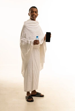 أداء مناسك الحج والعمرة، بورتريه لشاب عربي خليجي سعودى يرتدي ثياب الإحرام يحمل بيده زجاجة مياة، الارتواء بماء زمزم، صورة الجسم بالطول الكامل، خلفية بيضاء