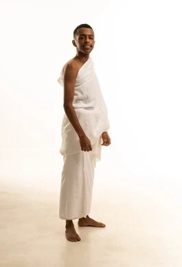 Performing the rituals of Hajj and Umrah, a side portrait of a smiling Saudi Arabian Gulf Arab Muslim man wearing Ihram clothing, the concept of the pillars of Islam, looking up, white background.