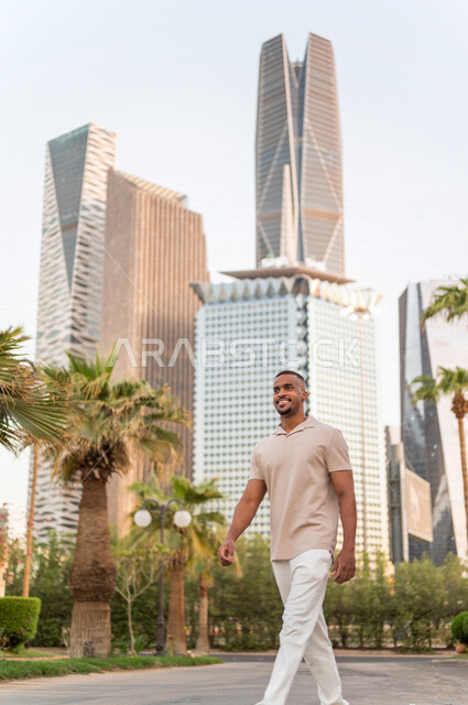 شاب عربي خليجي سعودي أسمر يقوم بجولة داخل مدينة الملك عبدالله المالية ( كافد ) في مدينة الرياض في المملكة العربية السعوية  ، إطلالة رائعة لأبراج المدينة ، جولة سياحية في المدينة