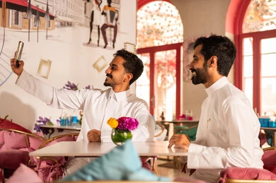 التقاط صور السيلفي التذكارية عبر الجوال ، توثيق اللحظات السعيدة ، كوفي شوب راقي بالمملكة العربية السعودية، تعابير السعادة والسرور بلمة الرفاق، تطوير العلاقات الإجتماعية، قضاء وقت ممتع مع الأصدقاء، الاستمتاع بالاجواء السعيده ، صديقان عربيان خليجيان سعوديان يجلسان على طاولة في المقهى