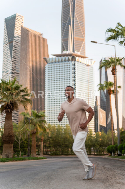 شاب عربي خليجي سعودي أسمر يمارس رياضة الجري في إحدى منتزهات الرياض ، المحافظة على اللياقة و الصحة البدنية ، ممارسة رياضة الجري في الهواء الطلق في مدينة الملك عبدالله المالية ( كافد ) في الرياض في السعودية