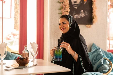 كوفي شوب راقي بالمملكة العربية السعودية، تعابير السعادة والسرور ،قضاء أوقات ممتعة مع الأصدقاء، النقاش والحوار في الأجواء الهادئة، مشاركة المشروبات الباردة ، صديقتان عربيتان خليجيتان سعوديتان ترتديان العباءة والحجاب تجلسان  في إحدى المقاهي الراقية