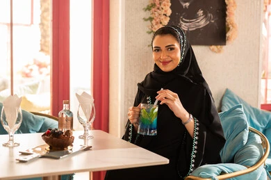تعابير السعادة والسرور ، كوفي شوب راقي بالمملكة العربية السعودية، قضاء أوقات ممتعة مع الأصدقاء، النقاش والحوار في الأجواء الهادئة، مشاركة المشروبات الباردة ، صديقتان عربيتان خليجيتان سعوديتان ترتديان العباءة والحجاب تجلسان  في إحدى المقاهي الراقية