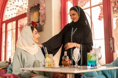 تعابير السعادة والسرور ، كوفي شوب راقي بالمملكة العربية السعودية، قضاء أوقات ممتعة مع الأصدقاء، النقاش والحوار في الأجواء الهادئة، مشاركة المشروبات الباردة ، صديقتان عربيتان خليجيتان سعوديتان ترتديان العباءة والحجاب تجلسان  في إحدى المقاهي الراقية