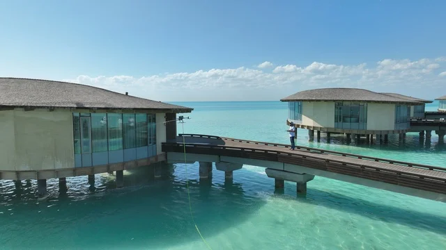 Famous places and tourist attractions in Qatar, a luxury resort over the waters of the Red Sea in tropical islands, the St. Regis Hotel in Doha, upscale hotels and residential resorts, modern design of wooden chalets overlooking the Arabian Gulf, tourism, tranquility, and beauty.