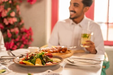 تبادل الأحاديث والاخبار, عزومة غداء لصديقان عربيان خليجيان سعوديان يقومان بتناول الأطعمة في أحد المطاعم الفاخرة، تعابير السرور والبهجة ،مائدة طعام مليئة بأصناف من المأكولات والمقبلات الشهية, ايماءات السعادة بقضاء اوقات ممتعه مع الاصحاب, لمة الاصدقاء على سفرة الإفطار الشهية