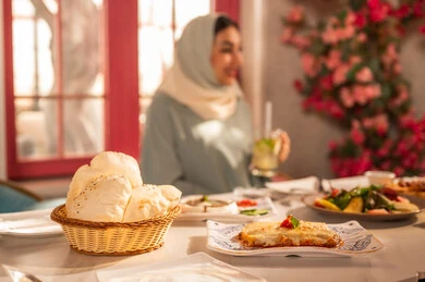 A gathering on the weekend, a dining table filled with a variety of delicious dishes and appetizers, gestures of happiness enjoying fun times with friends, a gathering of friends at a delicious breakfast table, a close-up picture of a lunch invitation for Saudi Gulf Arab friends enjoying food at a luxury restaurant.