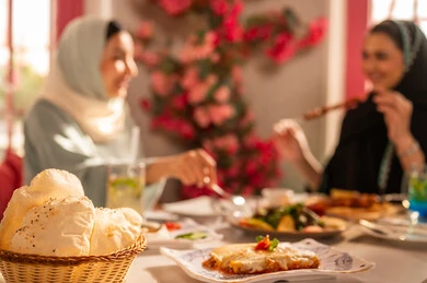 A gathering of friends at a delicious breakfast table, expressions of joy and happiness, a dining table filled with a variety of delicious dishes and appetizers, gestures of happiness spending enjoyable times with friends, a close-up image of a lunch invitation for Saudi Gulf Arab friends enjoying food at a luxury restaurant.