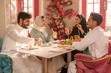 A close-up image of a lunch gathering for Saudi Gulf Arab friends enjoying food at a luxury restaurant, expressions of joy and happiness, a dining table filled with a variety of delicious dishes and appetizers, gestures of happiness spending enjoyable times with friends, a gathering of friends at a delicious breakfast table.