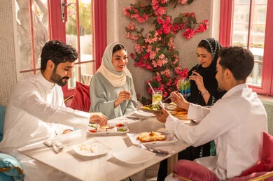 A dining table filled with a variety of delicious dishes and appetizers, gestures of happiness spending enjoyable times with friends, a gathering of friends at a delicious breakfast table, a close-up image of a lunch invitation for Saudi Gulf Arab friends enjoying food at a luxury restaurant.