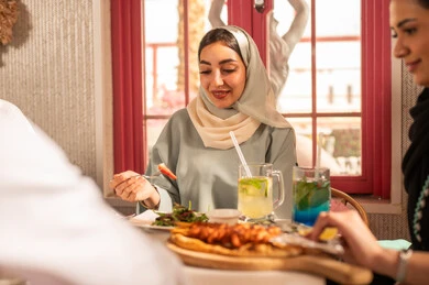 A dining table filled with a variety of delicious dishes and appetizers, gestures of happiness spending enjoyable times with friends, a gathering of friends at a delicious breakfast table, a close-up image of a lunch invitation for Saudi Gulf Arab friends enjoying food at a luxury restaurant.