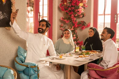 توثيق اللحظات السعيدة  باستخدام الجوال ، مائدة طعام مليئة بأصناف من المأكولات والمقبلات الشهية, ايماءات السعادة بقضاء اوقات ممتعه مع الاصحاب, لمة الاصدقاء على سفرة الإفطار الشهية, صورة مقربة لعزومة غداء لاصدقاء عرب خليجيين سعوديين  يقومون بتناول الأطعمة في أحد المطاعم الفاخرة