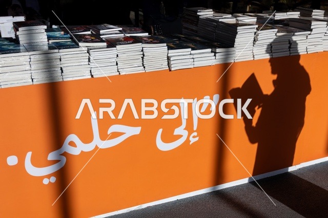 جذب السياح من أنحاء العالم، معلم ومكان سياحي ثقافي مشهور، قضاء وقت ممتع في شراء الروايات المفيدة للتعلم والتثقف، ظل رجل عربي خليجي سعودي يقوم بقراءة الكتب في معرض الكتاب الدولي في الرياض، معارض وفعاليات في المملكة العربية السعودية