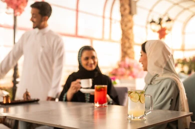 الاستمتاع بالمشروبات الساخنه ، كوفي شوب راقي بالمملكة العربية السعودية، تعابير السعادة والسرور بلمة الرفاق، تطوير العلاقات الإجتماعية، قضاء وقت ممتع مع الأصدقاء، الاستمتاع بالاجواء السعيده ، مجموعة اصدقاء عرب خليجيين سعوديين يجلسون على طاولة في المقهى