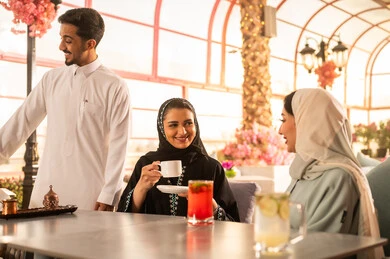 الاستمتاع بالاجواء السعيده ، كوفي شوب راقي بالمملكة العربية السعودية، تعابير السعادة والسرور بلمة الرفاق، تطوير العلاقات الإجتماعية، قضاء وقت ممتع مع الأصدقاء، الاستمتاع بالمشروبات الساخنه ، مجموعة اصدقاء عرب خليجيين سعوديين يجلسون على طاولة في المقهى