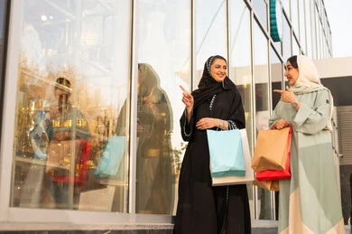 Having a good time, strolling and breathing in the fresh air outside, pride and appreciation for architectural progress, urban growth and development in Saudi Arabia, gestures of joy and happiness, two Arab Gulf Saudi friends wearing abayas and hijabs looking at something during the day.
