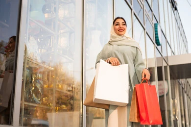 Pride and appreciation for architectural progress, urban growth and development in Saudi Arabia, gestures of joy and happiness, strolling and breathing in the fresh air outside, an Arab Gulf Saudi woman wearing an abaya and hijab looking at something during the day.