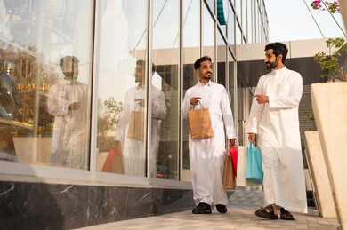 رجلان عربيان خليجيان سعوديان يتجولان ويتبادلان الاحاديث بايماءات الود والسعادة، التجول واستنشاق الهواء النقي في الخارج, الفخر والاعتزاز بالتقدم المعماري ، النمو والتطور العمراني في السعودية