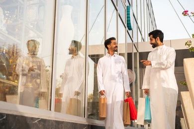 The growth and urban development in Saudi Arabia, strolling and breathing fresh air outside, pride and appreciation for architectural progress, two Arab Gulf Saudi men are walking and exchanging conversations with gestures of warmth and happiness.