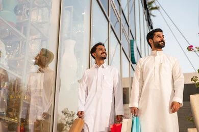 التجول واستنشاق الهواء النقي في الخارج, الفخر والاعتزاز بالتقدم المعماري ، النمو والتطور العمراني في السعودية ، رجلان عربيان خليجيان سعوديان يرتديان الثوب الابيض ينظران الى شيء ما في وقت النهار