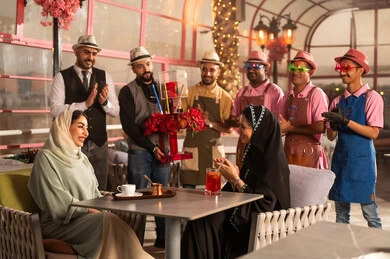 Expressions of affection and intimacy, giving gifts on happy occasions, a Gulf Arab Saudi woman wearing an abaya and hijab celebrating holidays and events with her friend, joyful atmosphere and celebrations, a bouquet of red roses, the concept of enjoyment and entertainment.