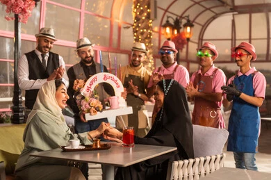 تعابير الود والالفة ،الاستمتاع بالمناسبات وأعياد الميلاد، امراه عربية خليجية سعودية ترتدي العباءه والحجاب تحتفل بعيد ميلاد صديقتها ، أجواء فرحة  واحتفالات ، المشاركة بأعياد ميلاد، كيكة مزينة مع الشموع ، مفهوم الاستمتاع  والترفيه