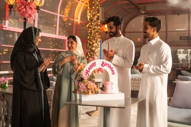 أجواء فرحة  واحتفالات ،  عائلة عربية خليجية سعودية تحتفل بعيد ميلاد صديقتهم فى المقهى ، المشاركة بأعياد ميلاد، كيكة مزينة مع الشموع ، مفهوم الاستمتاع  والترفيه ، تعابير الود والالفة