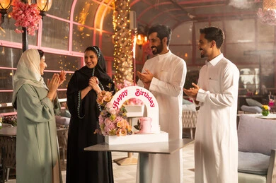 أجواء فرحة  واحتفالات ،  عائلة عربية خليجية سعودية تحتفل بعيد ميلاد صديقتهم فى المقهى ، المشاركة بأعياد ميلاد، كيكة مزينة مع الشموع ، مفهوم الاستمتاع  والترفيه ، تعابير الود والالفة