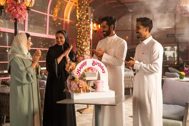 Celebrating birthdays, a Saudi Gulf Arab family celebrates their friend's birthday, joyful atmosphere and celebrations, participating in birthday parties, a decorated cake with candles, the concept of enjoyment and entertainment, expressions of affection and warmth.