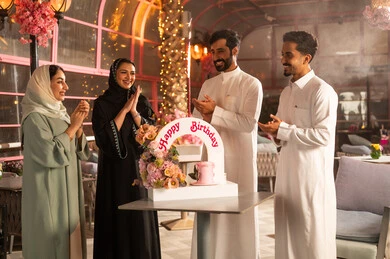 Celebrating birthdays, a Saudi Gulf Arab family celebrates their friend's birthday, joyful atmosphere and celebrations, participating in birthday parties, a decorated cake with candles, the concept of enjoyment and entertainment, expressions of affection and warmth.