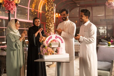 عائلة عربية خليجية سعودية تحتفل بعيد ميلاد صديقتهم فى المقهى ، أجواء فرحة  واحتفالات ، المشاركة بأعياد ميلاد، كيكة مزينة مع الشموع ، مفهوم الاستمتاع  والترفيه ، تعابير الود والالفة، الاحتفال بأعياد الميلاد