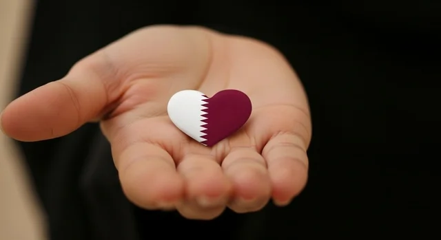 The concept of love and belonging to the country, national holidays and occasions, commemorating the founding of the state, celebrating Qatar National Day on December 18, a close-up image of a Qatari Gulf Arab woman wearing a hijab holding the Qatari flag shaped like a heart in her hand with gestures of pride and belonging, national symbols and cultures, love for the homeland and belonging.