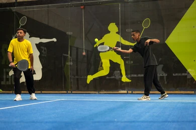 Youth sports and recreational activities, training to master the game of paddle, doing tennis exercises, participating in matches and tournaments with challenge and determination, a young Arab Gulf Saudi man wearing sportswear playing a tennis match alongside a female partner, expressions and gestures indicating enthusiasm and engagement in the exercise.
