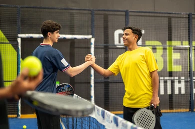 Fitness and physical agility, two Arab Gulf friends from Saudi Arabia wearing sports attire shaking hands, engaging in matches and tournaments with challenge and determination, performing tennis exercises, a close-up shot of a Saudi Arabian Gulf boy holding the ball and racket in his hands.