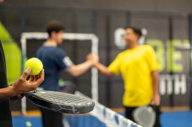 Two Arab Gulf Saudi friends wearing sports attire are shaking hands, engaging in matches and tournaments with challenge and determination, performing tennis exercises, a close-up shot of a Saudi Gulf Arab boy holding the ball and racket in his hands, fitness and physical agility.