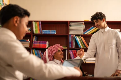 دعم العلاقات الودية بين الطلبة، الترحيب و السلام و إلقاء التحية، العمل الجماعي والتعاون بين الزملاء، مفهوم الاجتهاد وطلب التفوق، التربية والتعليم فيالمملكة العربية السعودية، مجموعه من الطلاب العربيون الخليجيون السعوديون يرتدون الثوب الابيض يجلسون داخل مكتبه المدرسة، استخدام جهاز التابلت فى الدراسة
