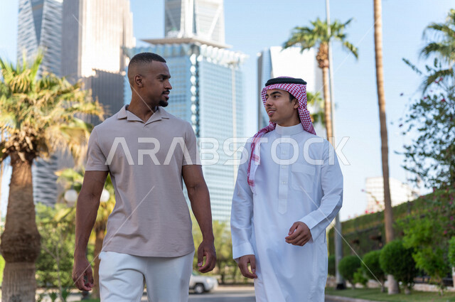 Two Saudi Arabian Gulf youths taking a tour inside the financial city, recreation and hiking in the fresh air, meeting and acquaintance, meeting friends, spending quality time in King Abdullah Financial City (KAFED) in the city of Riyadh, Kingdom of Saudi
