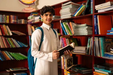 الاستمتاع بقراءة الكتب، طالب عربي سعودي خليجي يقوم بقراءة كتاب من المكتبة المدرسية، مفهوم القراءه والثقافه, بيئه مدرسيه تعليميه متطوره, مدارس أكاديميه في المملكة العربية السعودية