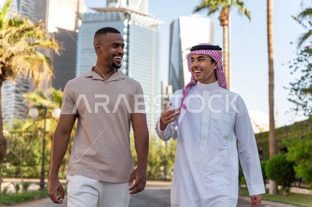 شابان عربيان خليجيان سعوديان يقومان بجولة داخل المدينة المالية ، الاستجمام و التنزه في الهواء الطلق ، لقاء و تعارف ، مقابلة أصدقاء ، قضاء وقت ممتع في مدينة الملك عبد الله المالية ( كافد ) في مدينة الرياض ، المملكة العربية السعودية