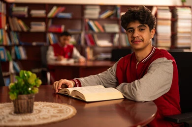 Education and study in Saudi Arabia, visiting the school library, spending free time learning and self-cultivation, love of culture and exploration, an Arab Gulf Saudi student wearing school uniform reading a book, developing reading skills for students, interest in browsing useful books. Education and study in Saudi Arabia, visiting the school library, spending free time learning and self-cultivation, love of culture and exploration, an Arab Gulf Saudi student wearing school uniform reading a book, developing reading skills for students, interest in browsing useful books.